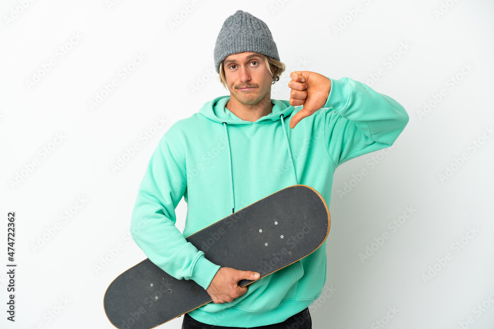 Young skater blonde man isolated on white background showing thumb down with negative expression