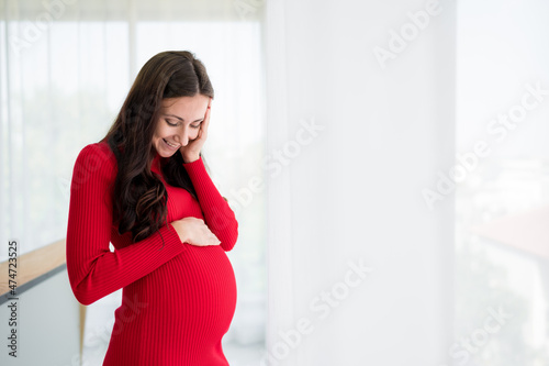 Pictures of new mothers, Europeans, Russians, pregnant Standing by the window, holding his tummy, smiling happily in the bedroom. wearing red maternity clothes Free Download Pictures of new mothers, Europeans, Russians, pregnant Standing by the window, holding his tummy, smiling happily in the bedroom. wearing red maternity clothes - GFXLoad