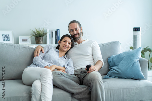 Caucasian loving couple watch movie together in living room at home.
