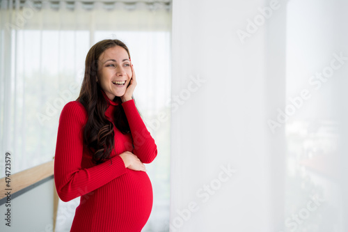 Pictures of new mothers, Europeans, Russians, pregnant Standing by the window, holding his tummy, smiling happily in the bedroom. wearing red maternity clothes Free Download Pictures of new mothers, Europeans, Russians, pregnant Standing by the window, holding his tummy, smiling happily in the bedroom. wearing red maternity clothes - GFXLoad