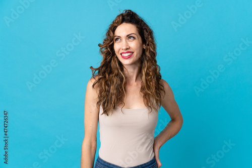 Young caucasian woman isolated on blue background thinking an idea while looking up © luismolinero