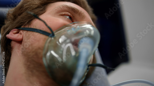 Injured man in oxygen mask lying on stretchers in ambulance car photo