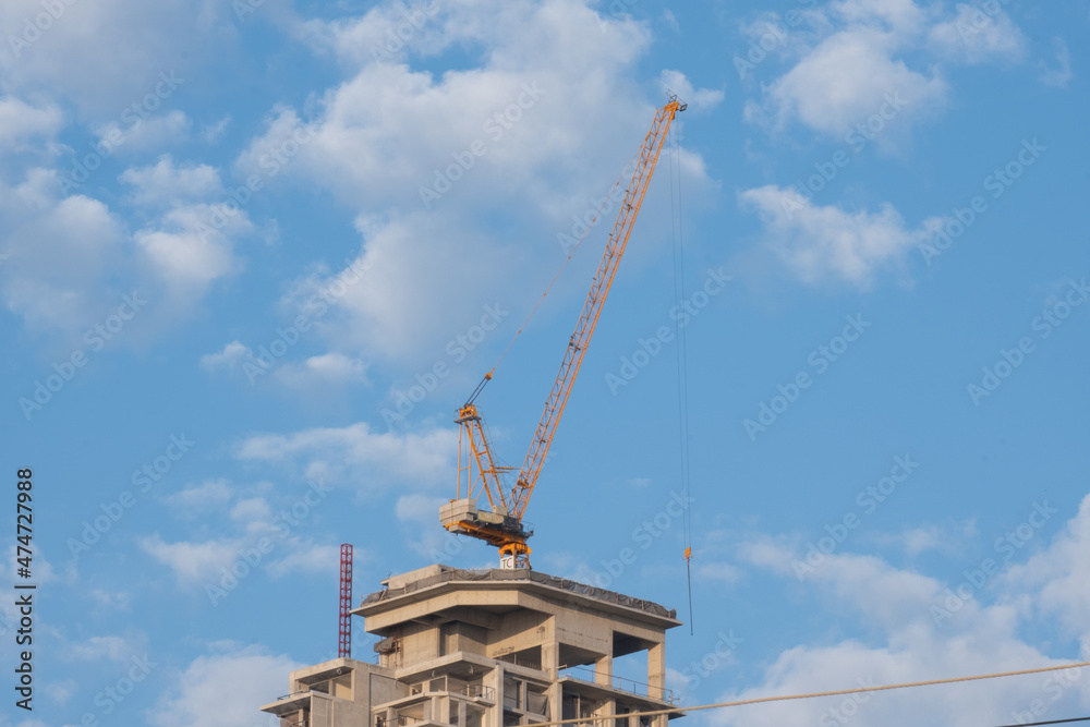 Construction crane on top of a building with blue sky