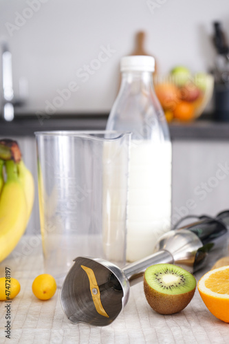 Home kitchen with ripe fruit table and hand blender, vertically.