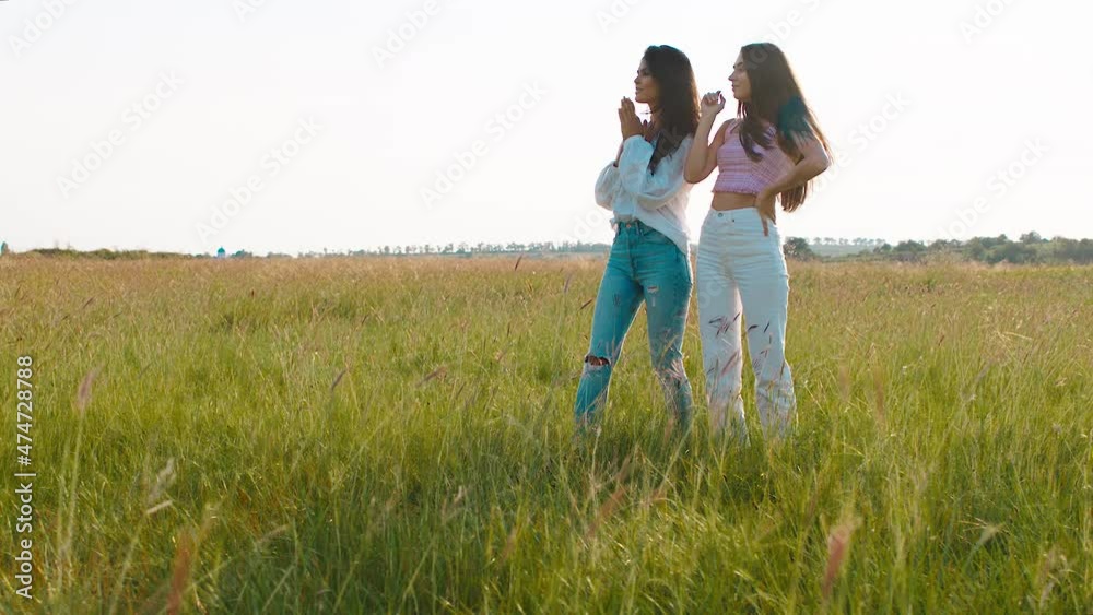 In front of the camera attractive charismatic happy ladies enjoy the landscape in the middle of amazing large green field In front of the camera attractive charismatic happy ladies enjoy the landscape in the middle of amazing large green field