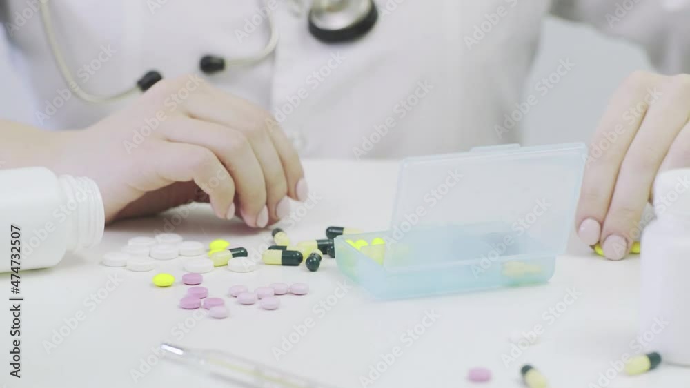 Close-up of a pillbox with different tablets. A person's hands put pills in a pillbox Close-up of a pillbox with different tablets. A person's hands put pills in a pillbox