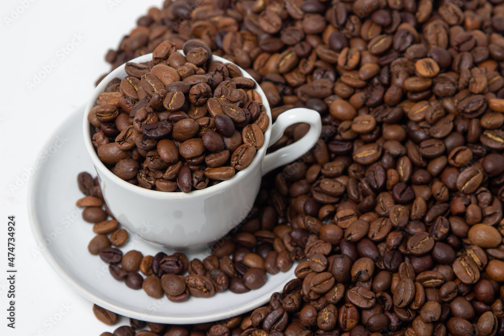 Coffee beans on a white background. A coffee cup full of coffee beans. Large serving of caffeine Coffee beans on a white background. A coffee cup full of coffee beans. Large serving of caffeine