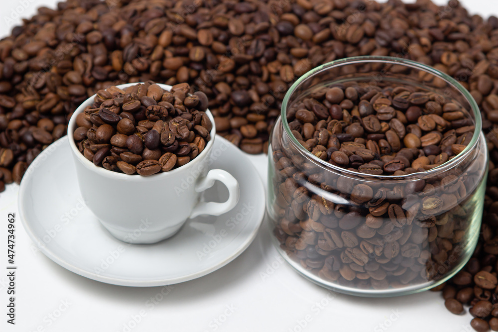 Fototapeta premium Coffee beans on a white background. A coffee cup full of coffee beans. Large serving of caffeine