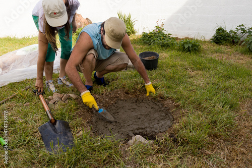 Pareja hombre y mujer latinos preparando el suelo en el jardín verde para construir un fogón con piedras naturales. Concepto de bioconstrucción ecológica, herramientas de jardinería, trabajo en equipo