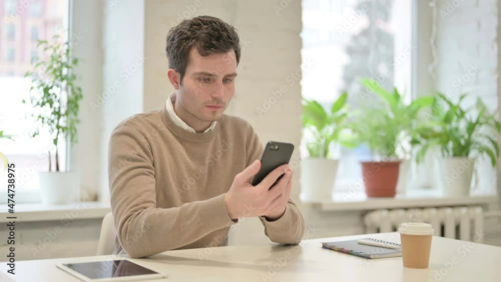 Attractive Man using Smartphone in Office Attractive Man using Smartphone in Office