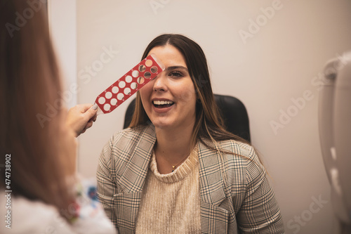 An Optometrist examines a woman's eye through a retinoscopy examination through Schiascopy rules. photo