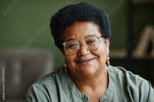 Close up portrait of kind black senior woman smiling at camera at home, copy space