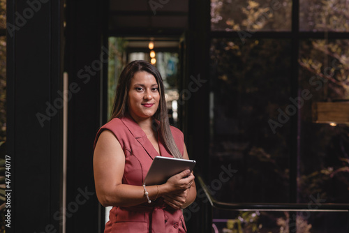 Hermosa mujer latina de negocios con una tableta digital en sus manos	
 photo