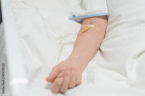 Close-up of senior patient lying under a drip in the hospital bed