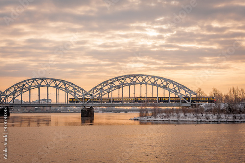 Electric train on the steel railway bridge at sunrise spring morning. Riga, Latvia. © Regina