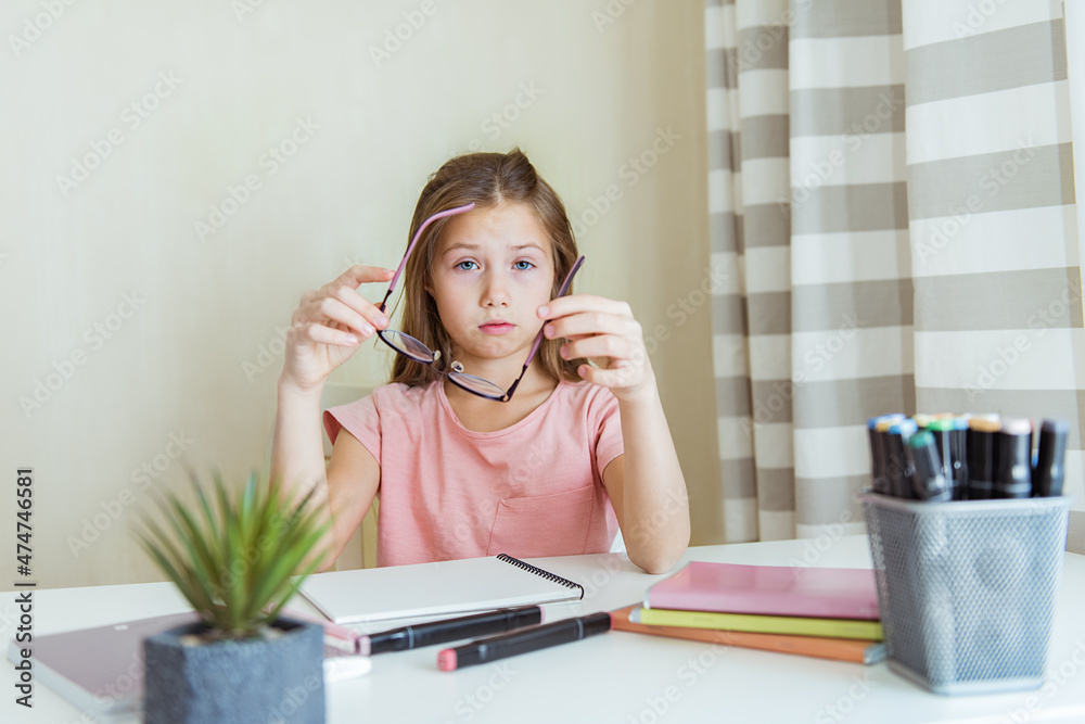 Φωτογραφία Tired teen girl with taking off glasses while sitting at home after hard school homework with laptop computer