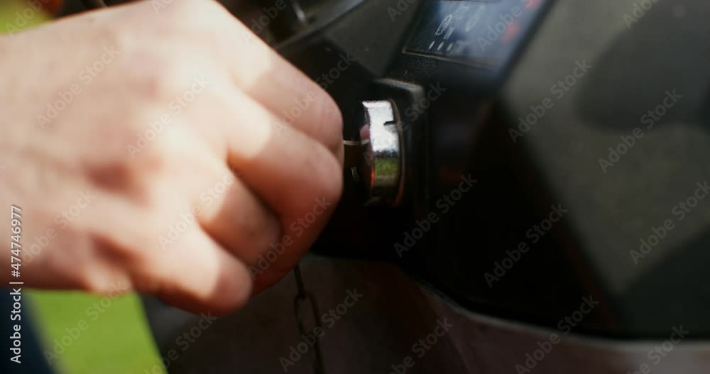 A man gets into tractor and turns the key in the ignition, close-up of the key A man gets into tractor and turns the key in the ignition, close-up of the key