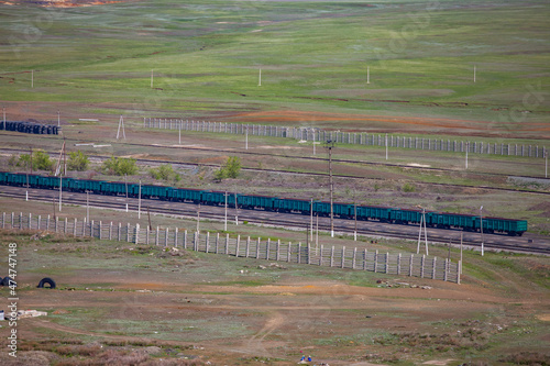 Aerial view on geen train open wagons in green steppe. Grey snow fences. Grey concrete electric poles. photo