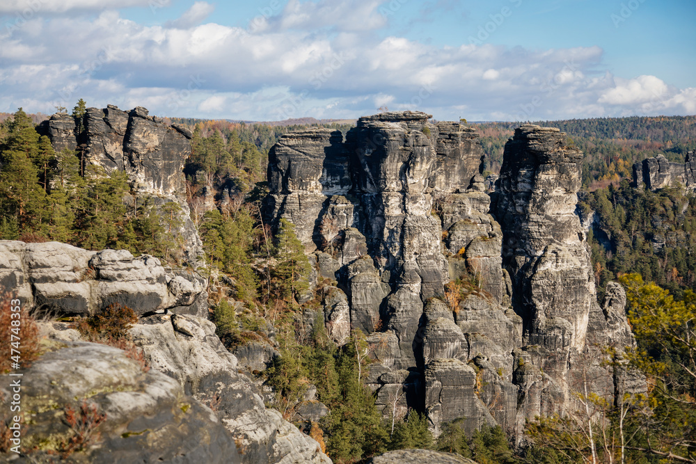 Saxon Switzerland National Park, Germany, 6 November 2021: Basteiaussicht or Bastei Rock Formations in Elbe River Valley, Sandstone Mountains Path, autumn forest landscape at sunny day, rocky valley