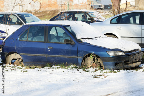 Stary wrak samochodu bez kół na parkingu w mieście. 