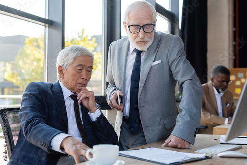 senior interracial business partners looking at contract while working in office
