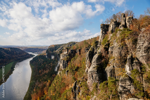 Saxon Switzerland National Park, Germany, 6 November 2021: Basteiaussicht or Bastei Rock Formations in Elbe River Valley, Sandstone Mountains Path, autumn forest landscape at sunny day, rocky valley