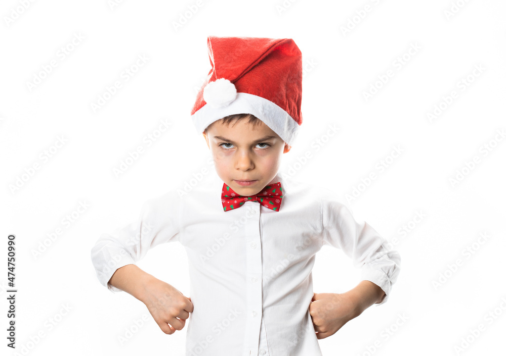 Little funny serious boy in Santa Claus hat and Christmas bow-tie against white background Little funny serious boy in Santa Claus hat and Christmas bow-tie against white background