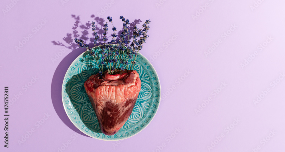 Naklejka premium Top view of animal heart filled with lavender flowers on turquoise plate. Creative love, St Valentine holiday, concept.
