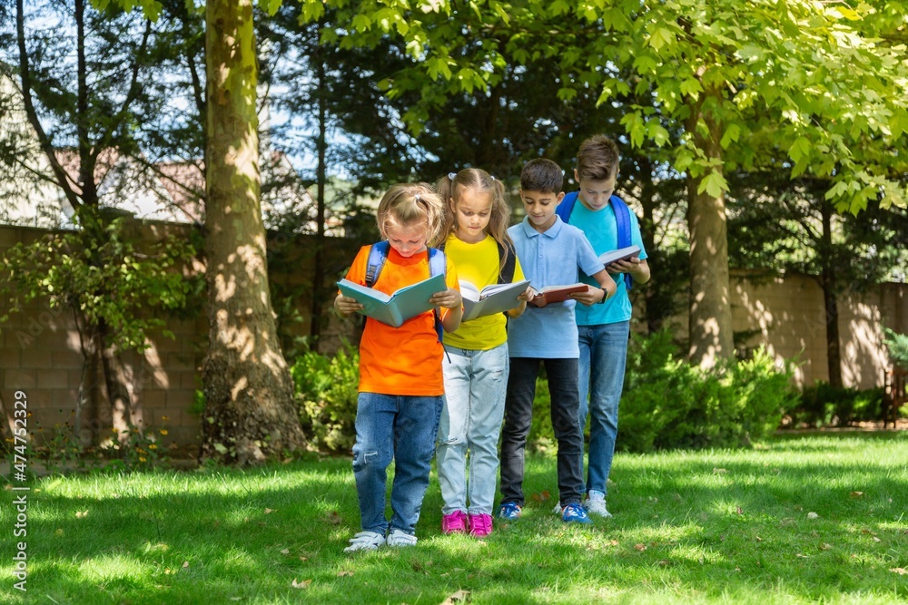 Group of happy school child with book in outdoor park Group of happy school child with book in outdoor park