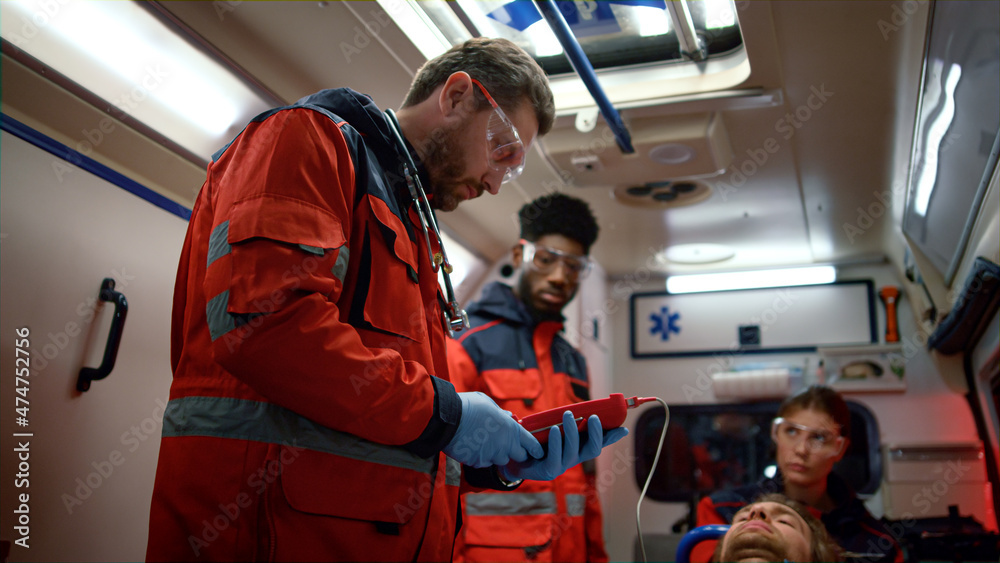Mixed race paramedics checking oxygen blood saturation level of patient Mixed race paramedics checking oxygen blood saturation level of patient