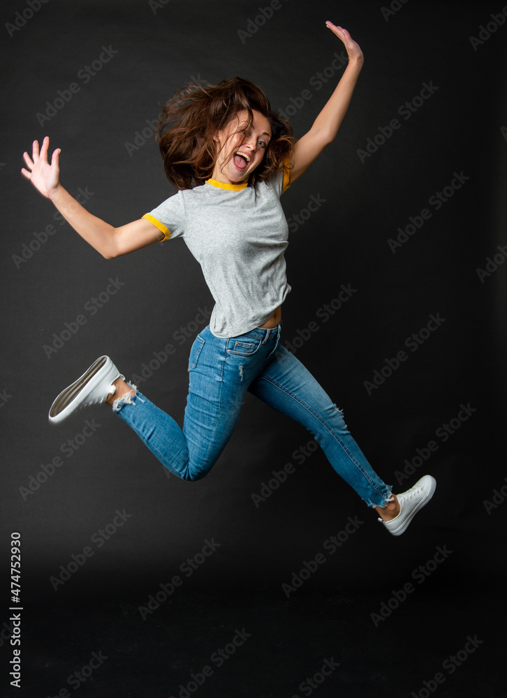 Happy cool ecstatic energetic girl jumping up midair dark background, jump
