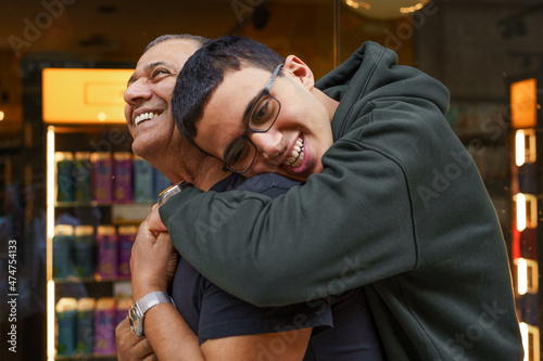 Hug for dad. A teen boy leans over to hug his father, who to be smiling at him.