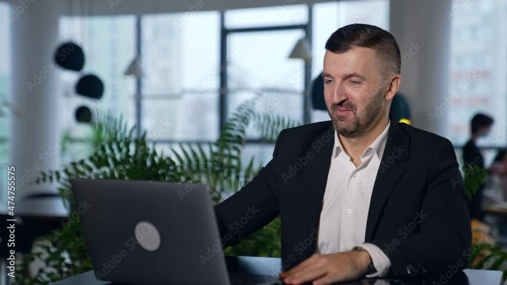 Bearded man wearing official suit opens laptop and starts conversation. Using gadgets in business negotiations. Blurred backdrop. Bearded man wearing official suit opens laptop and starts conversation. Using gadgets in business negotiations. Blurred backdrop.
