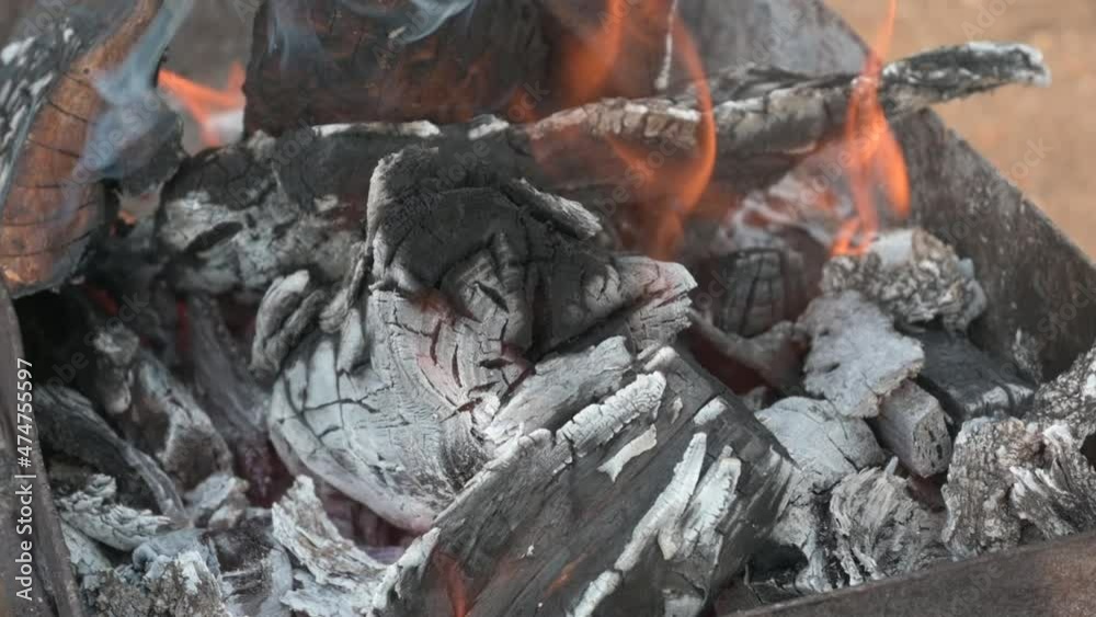 Burning log of wood close-up as abstract background. The hot embers of burning wood log fire. Firewood burning on grill. Texture fire bonfire embers. Smoldering fire. Slow motion. Burning log of wood close-up as abstract background. The hot embers of burning wood log fire. Firewood burning on grill. Texture fire bonfire embers. Smoldering fire. Slow motion.