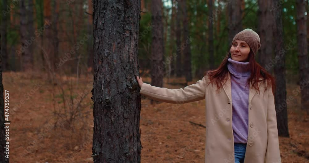Pretty young woman walks through the forest and runs her hand through the trees. Woman's hand touches a tree trunk. Autumn walk in the forest on a cool day. 4k, ProRes Pretty young woman walks through the forest and runs her hand through the trees. Woman's hand touches a tree trunk. Autumn walk in the forest on a cool day. 4k, ProRes