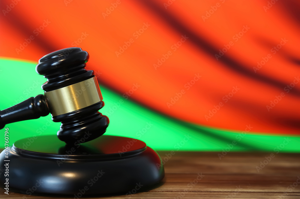 Closeup of isolated judge wood gavel with blurred belarus flag background (focus on hammer head)