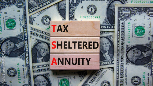 TSA, tax sheltered annuary symbol. Concept words TSA, tax sheltered annuary on wooden blocks. Beautiful background from dollar bills, copy space. Business and TSA, tax sheltered annuary concept.
