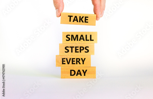 Take small steps every day symbol. Wooden blocks with words Take small steps every day. Beautiful white background, copy space. Businessman hand. Business, step every day concept. photo