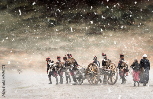 Napoleon soldiers marching in falling snow and pulling a cannon with them. No recognizable people in the image photo