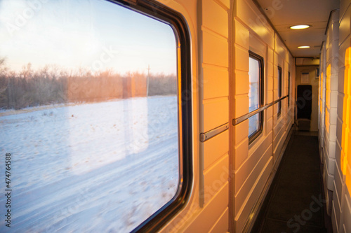 view from the window of a high-speed train in the aisle of a compartment, at sunset, the foreground and background are blurred with bokeh effect © Torkhov