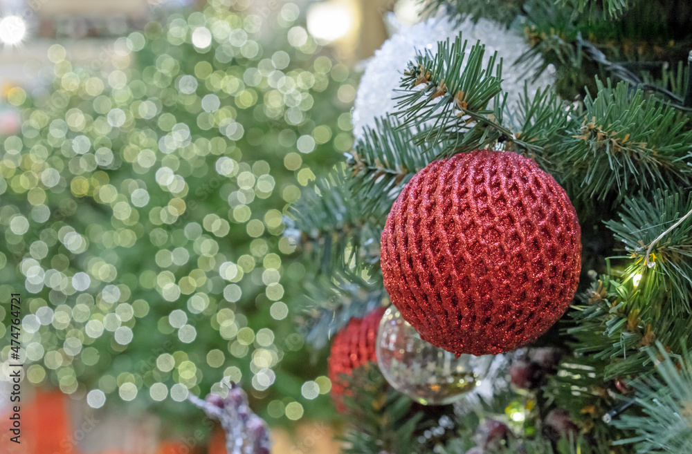 Red shiny Christmas ball with mesh ornament on bokeh background.