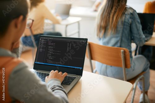 Close-up of high school student learns coding during computer class in classroom.