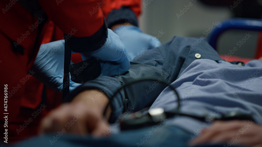 Obraz premium Man lying on stretchers. Medical worker putting tonometer on patient arm 