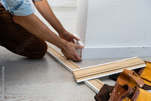 Mans hands putting white baseboard. photo
