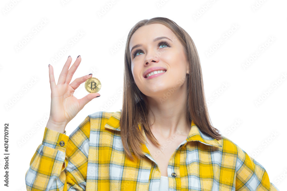 Closeup of cute smiling girl holding a physical bitcoin cryptocurrency in her hand isolated on white background. Concept of financial literacy, innovation, success Closeup of cute smiling girl holding a physical bitcoin cryptocurrency in her hand isolated on white background. Concept of financial literacy, innovation, success