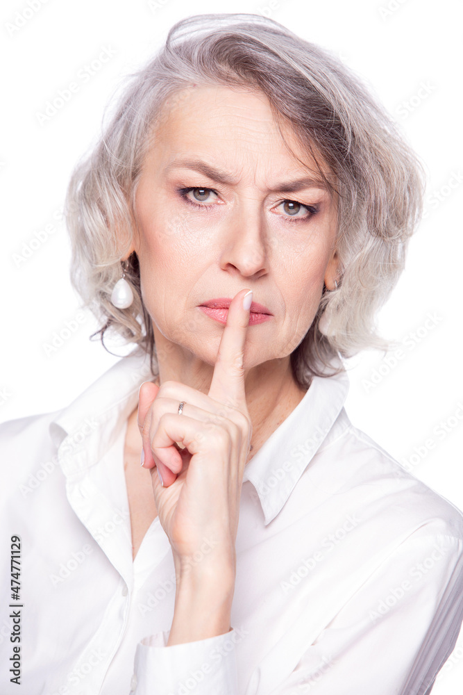 Middle aged beautiful woman putting her finger to her lips with a frown and stern look asking for quiet, isolated on white background Middle aged beautiful woman putting her finger to her lips with a frown and stern look asking for quiet, isolated on white background