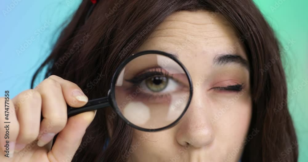 Young woman enlarges her eye with a magnifying glass. Young woman enlarges her eye with a magnifying glass.