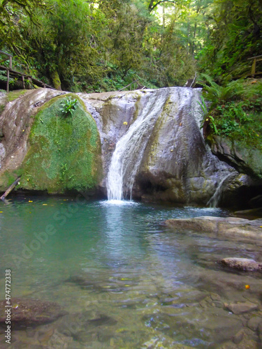 A waterfall flowing down from a small rock into a stream. Picturesque summer landscape Krasnodar region.