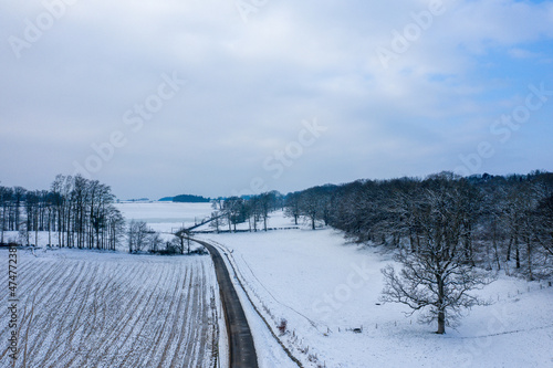 A road in the middle of fields and snow-covered trees in Europe, France, Normandy, between Dieppe and Fecamp, in Winter, on a sunny day. © Florent
