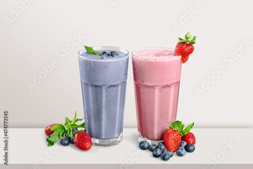 fresh milkshake with cream decorated berries portions on table.